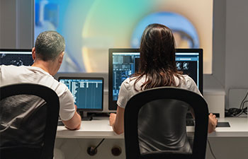 Radiologieassistenten analysieren Bilder an Computerbildschirmen.