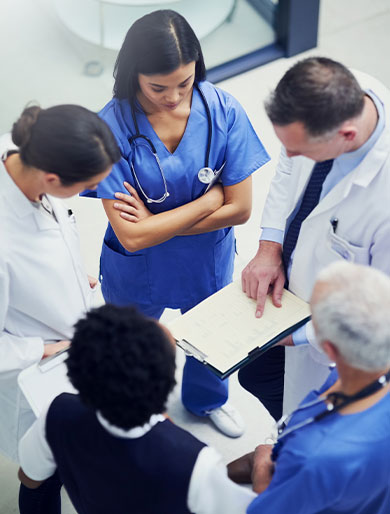Ein interdisziplin&auml;res medizinisches Team bespricht gemeinsam Unterlagen und stimmt sich zu wichtigen Fragen der Patientenversorgung ab.